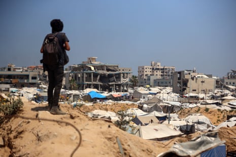 A man looks on at the crowded tents of displaced people among the destroyed buildings in Gaza City on 17 June 2025.
