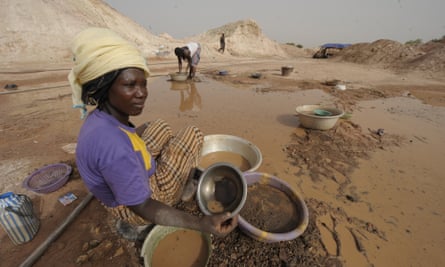 A woman sifts through mud as she looks for gold in Namisgma, the largest gold washing site in the country.