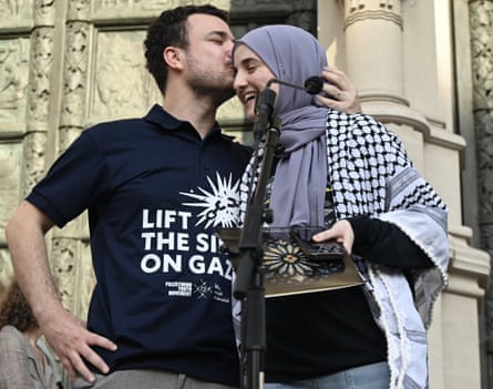A man who wears a shirt that says ‘lift the siege on Gaza’ kisses the temple of a woman who wears a headscarf and a keffiyeh around her shoulders