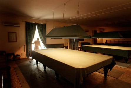 An employee draws the curtains in a room with a billiards table