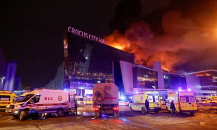 Vehicles of Russian emergency services are parked near the burning Crocus City Hall concert venue