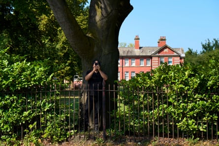 House, garden, and man in black with phone
