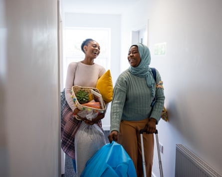 University students moving into their student accommodation in the North East of England. They are carrying bags/suitcases, laughing together.