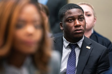 Man in suit looking attentively forward, with woman blurred in foreground.