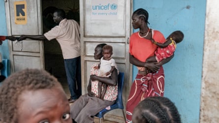 Mothers wait with their babies outside a doorway