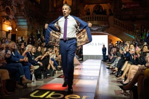 Andrew Cuomo holds his suit jacket open at the end of the runway