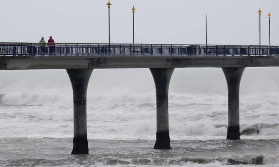 A couple walk on New Brighton pier as heavy rain continues in the city of Christchurch on May 31, 2021, after the area was pounded by heavy rains that forced authorities to declare a state of emergency in the province of Canterbury. (Photo by Sanka VIDANAGAMA / AFP) (Photo by SANKA VIDANAGAMA/AFP via Getty Images)