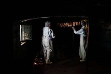 Workers hang hand-made chorizos in the farm’s traditional smoke room