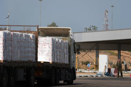 Trucks carrying aid wait at the Israeli side of the Kerem Shalom border crossing to southern Gaza