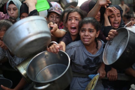 Palestinians, who face difficulties in accessing food due to the blockade imposed by Israel, wait to receive hot meals on 7 August.