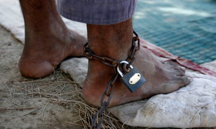 A man chained beneath a tree, as treatment for his mental illness, on the compounds of Mia Ali Baba Shrine in Nangarhar province, Afghanistan.