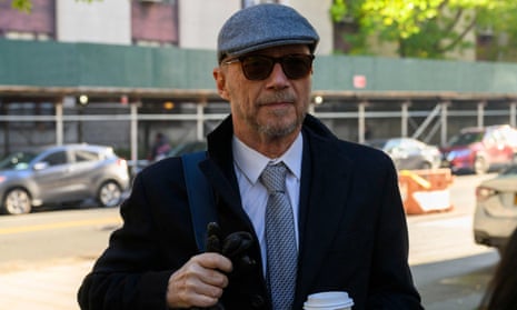 Man wearing a beret and sunglasses holding onto his backpack with one hand and a coffee in another