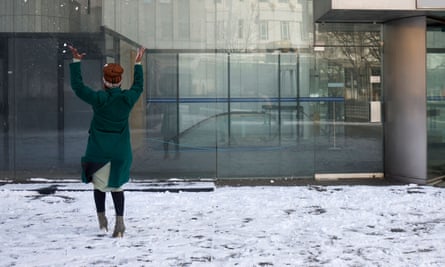 A woman throws snow in the air at a plaza in front of an office building in Johannesburg