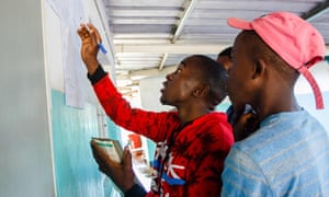 People look at ballot count results posted outside a polling station in Kambuzuma township, Harare