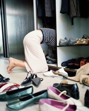 Woman on knees searching through shoes in wardrobe