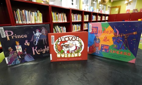 A display in a Mississippi city library shows three children's with LGBTQ+ characters. One is Prince and Knight, with a cover illustration showing a prince surrounded by kneeling princesses and a knight leaning against a horse. The book in the center is titled Santa's Husband and shows a Black Santa Claus hugging a white man with a white beard. The book on the right is Maiden and Princess, which shows a woman with a sword and a princess looking through a telescope.