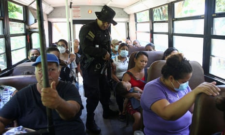 A policeman searches bus passengers near the area where three police officers were killed by alleged gang members, in Santa Ana, El Salvador, on Wednesday.