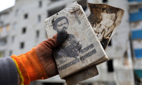 A book about 1917-21 anarchist leader Nestor Makhno is held outside a war-damaged building.