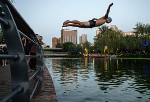 A man dives off a walkway at popular swimming area in Beijing.