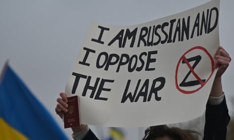 A protester holds a Russian passport and a poster with words ‘I am Russian and I oppose the war’ at a ‘Walk For Ukraine’ rally in the centre of Edmonton, Alberta, Canada.
