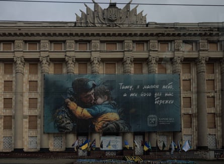 Large building with boarded-up windows and mural of a soldier carrying a child