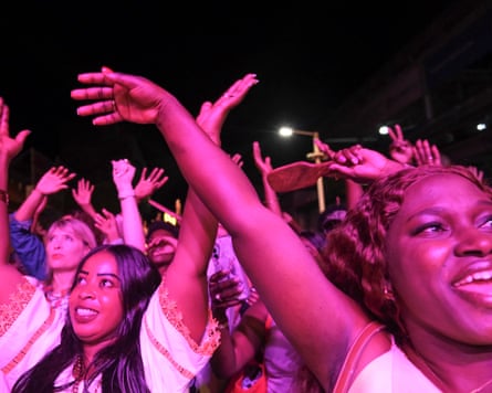 People dancing in a crowd under pink lights