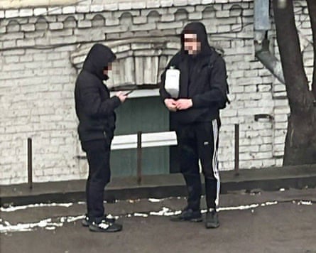 Two young men, one on his phone and the other carrying a box