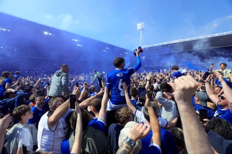 Ipswich Town fans and players celebrate on the pitch after securing promotion to the Premier League.