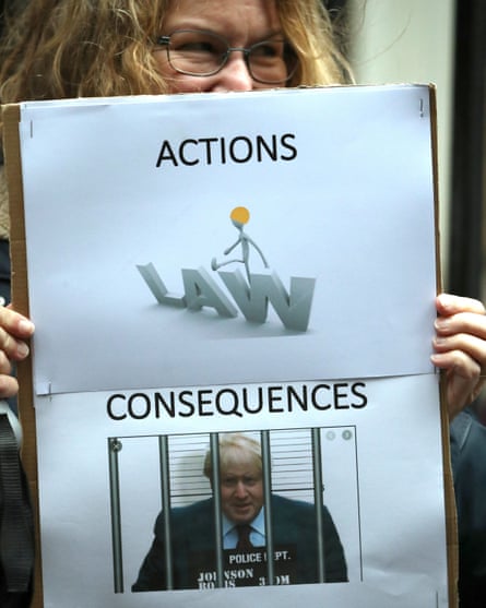 A protester holds a sign showing Boris Johnson in jail