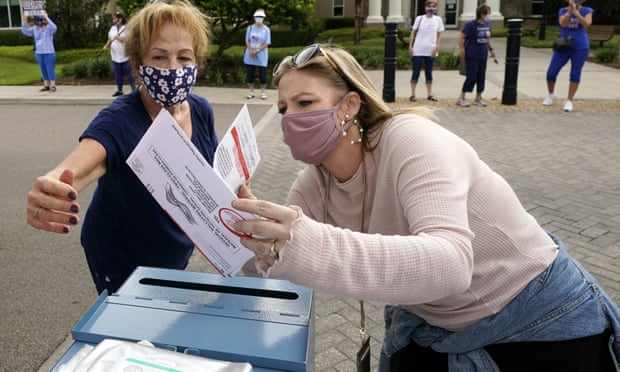 An elections employee checks ballots before dropping them in a collection box as a parade of over 300 golf carts supporting Joe Biden cast their ballots in The Villages, Florida.