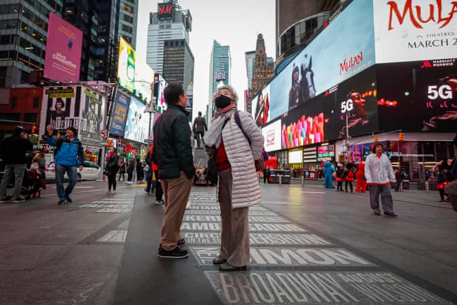 A pedestrian wearing a face mask stops in Times Square, Thursday, March 12, 2020, in New York. New York City Mayor Bill de Blasio said Thursday he will announce new restrictions on gatherings to halt the spread of the new coronavirus in the coming days. For most people, the new coronavirus causes only mild or moderate symptoms. For some it can cause more severe illness. 