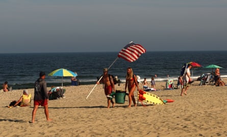 lifeguards carry gear and a US flag across the beach