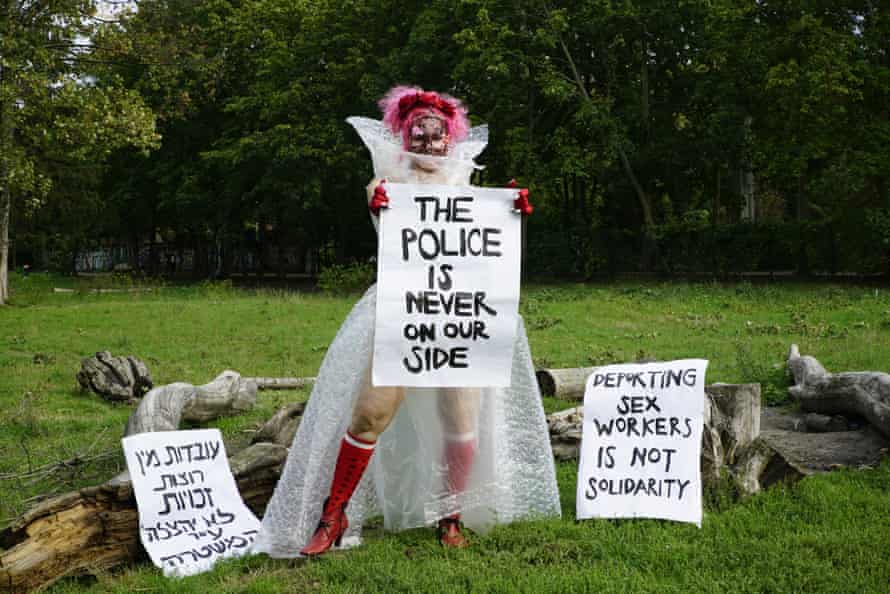woman wearing chiffon-voile dress holding placards challenging the role of the police from Mythical Creatures by Liad Hussein Kantorowicz.