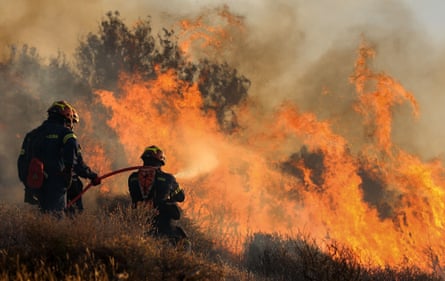 Two firefighters point their hosepipes towards flames