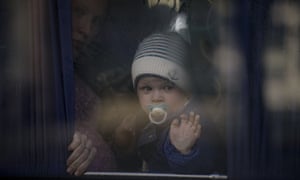 A refugee woman holds a baby while waiting on a bus for Ukrainian police to check papers and belongings in Brovary, Ukraine