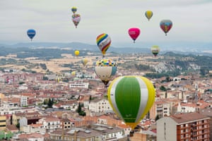 Hot-air balloons over an urban landscape with countryside in the distance