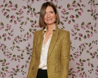 Plum Sykes smiles at the camera while standing in front of a floral background