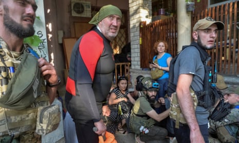 Servicemen and volunteers react during shelling, amid the evacuation of residents from a flooded area after the Nova Kakhovka dam breached in Kherson, Ukraine.