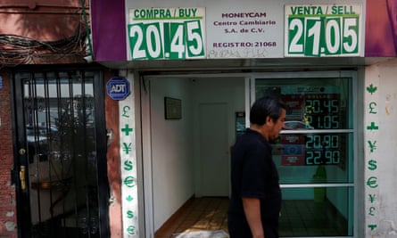 A man walks past a board displaying the exchange rate of the Mexican peso against the US dollar in Mexico City, on 9 January.
