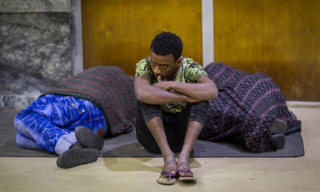 Zeynu Abebe, 19, sits between two sleeping people at Addis Ababa airport after being deported from Saudi Arabia