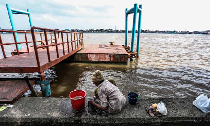A woman washes clothes near the river at a slum area in Palembang