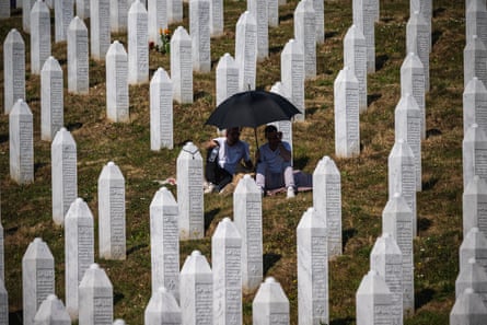 People sit under an umbrella in a cemetery