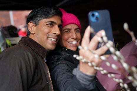 Sunak poses for a selfie with a woman in a pink beanie.