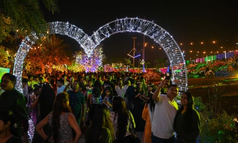 People gather at the sea promenade, lit up during sunset on New Year’s Eve in Mumbai