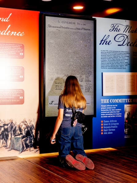 A person kneels on the ground to sign a virtual version of the American constitution
