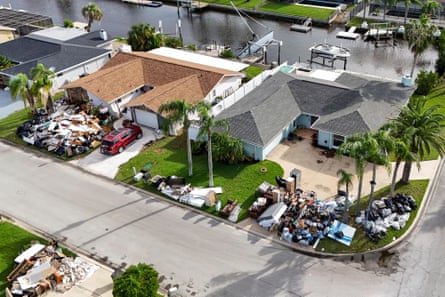 Aerial view of intact homes with green lawns covered in broken debris.