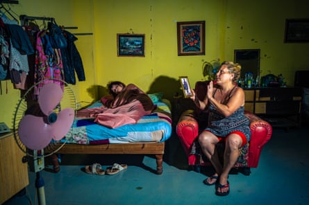 Marlene prays as she holds a photo of her deceased parents, with her daughter Keyla María, 17 in La Coubre shelter