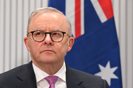 A man with short grey hair and black glasses.