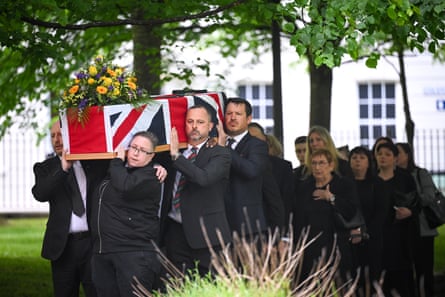 Mourners carry the coffin of James Kirby covered in a union flag
