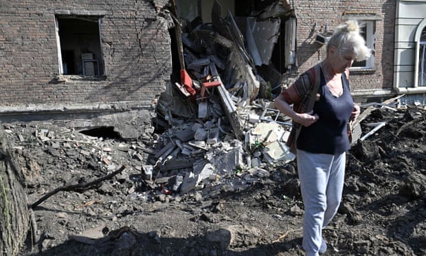A local resident walks in front of a crater from a missile strike at a residential building in the Ukrainian town of Bakhmut